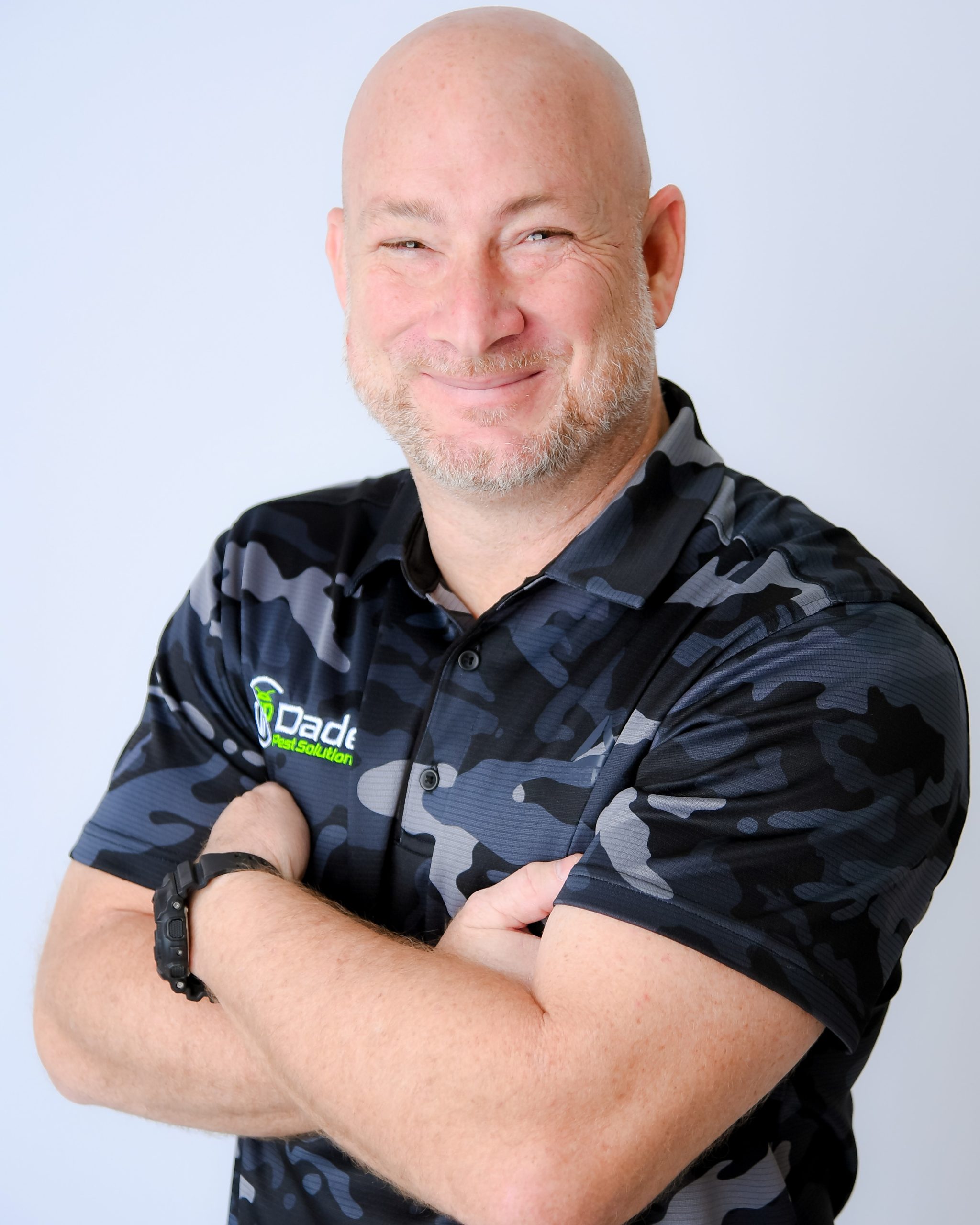 Shaun Judy wearing a Dade Pest Solutions shirt with arms folded.